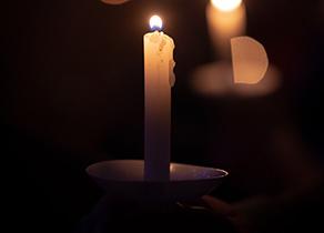 一支蜡烛在黑暗的背景下点燃，其他蜡烛的焦点不清晰，蒂姆·昂弗里斯拍摄